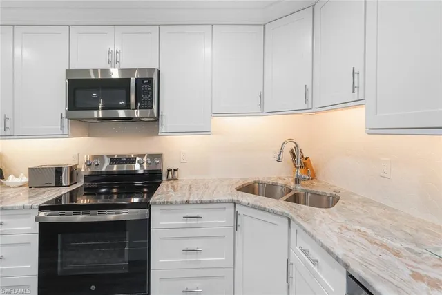 a kitchen with stainless steel appliances granite countertop white cabinets and a stove a oven with white countertops