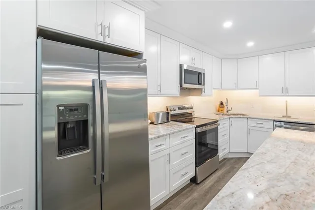 a kitchen with a refrigerator a stove top oven and cabinets