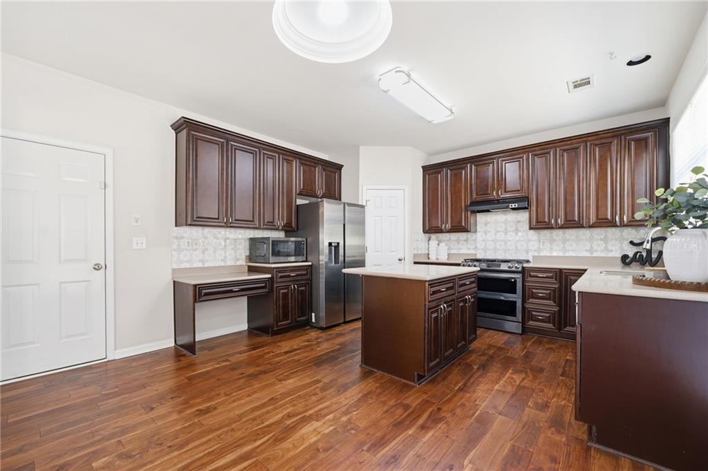 310 Hammersmith Drive Suwanee, GA 30024 - Photo 14 of 55 a kitchen with granite countertop wooden floors a stove and a refrigerator