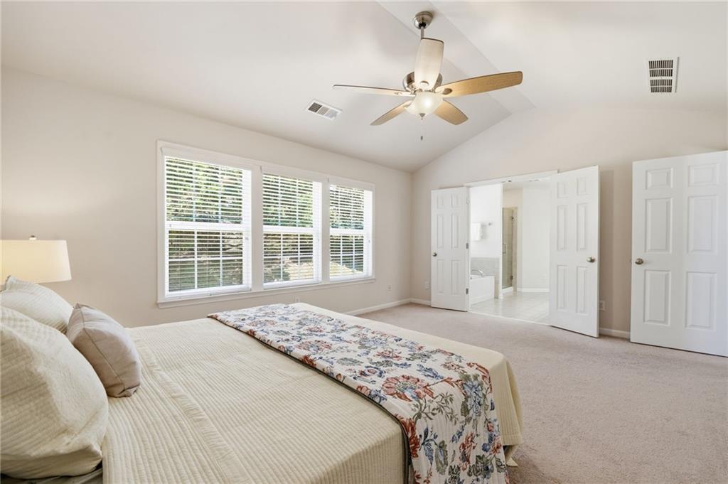 310 Hammersmith Drive Suwanee, GA 30024 - Photo 32 of 55 a spacious bedroom with a large bed and a chandelier