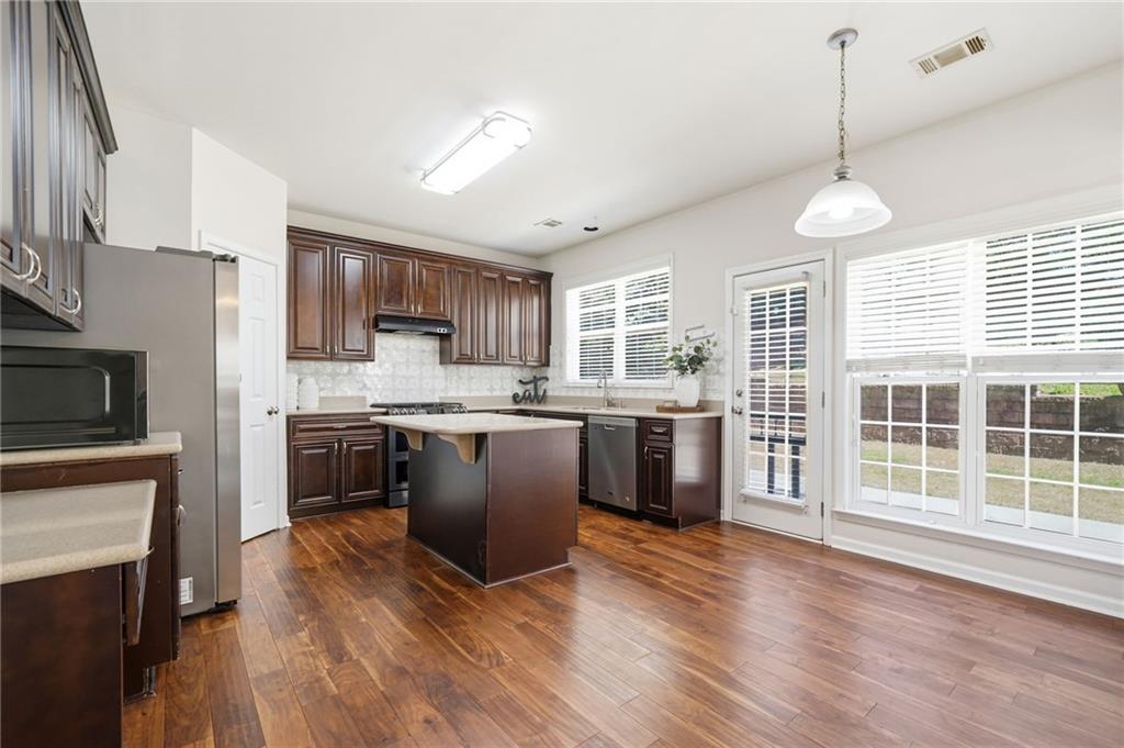 310 Hammersmith Drive Suwanee, GA 30024 - Photo 9 of 55 a kitchen with stainless steel appliances granite countertop a refrigerator a stove top oven a sink cabinets and wooden floor