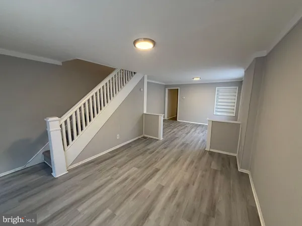 a view of an empty room with wooden floor and stairs