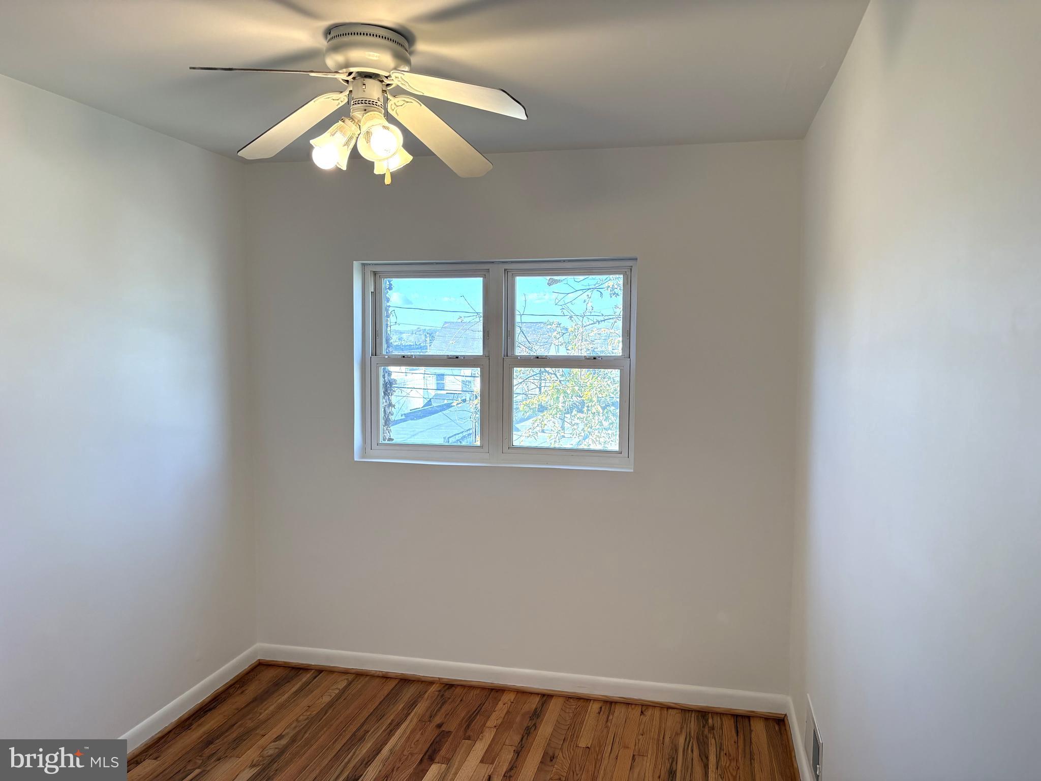 3820 2nd Street Baltimore, MD 21225 - Photo 14 of 23 an empty room with a chandelier fan and windows