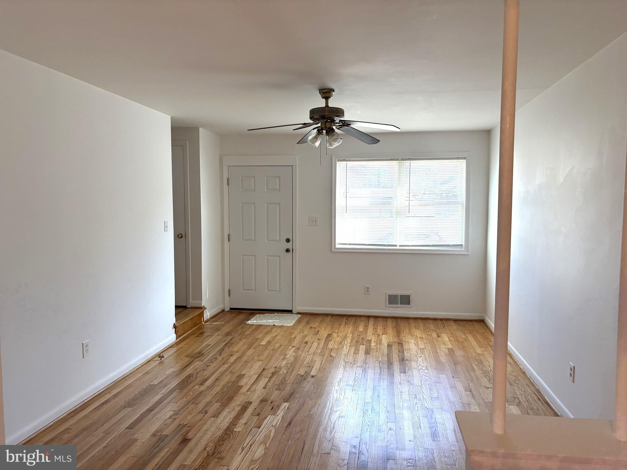 3820 2nd Street Baltimore, MD 21225 - Photo 2 of 23 an empty room with wooden floor chandelier fan and windows