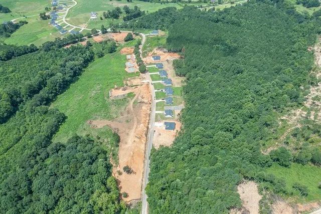 an aerial view of residential houses with outdoor space and trees all around