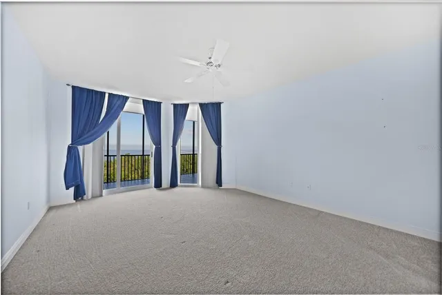 an empty room with wooden floor and windows with curtains