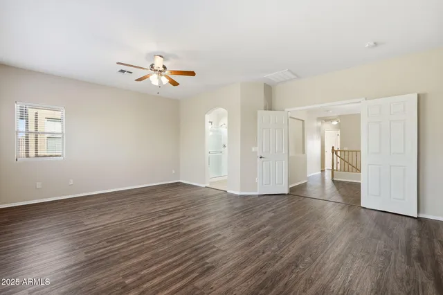 a view of empty room with wooden floor and fan