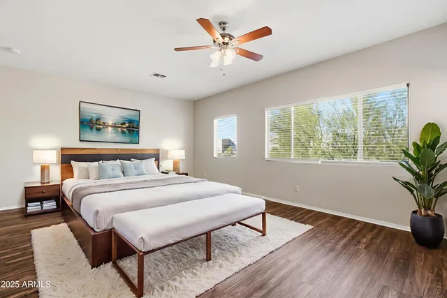 a bedroom with a bed a tv and wooden floor