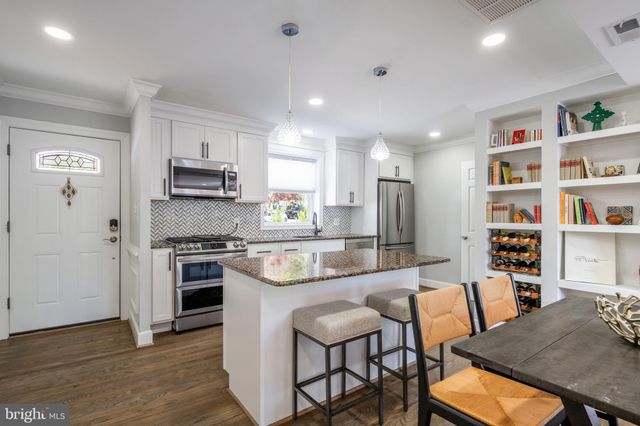 a large kitchen with stainless steel appliances a stove a refrigerator a dining table and chairs