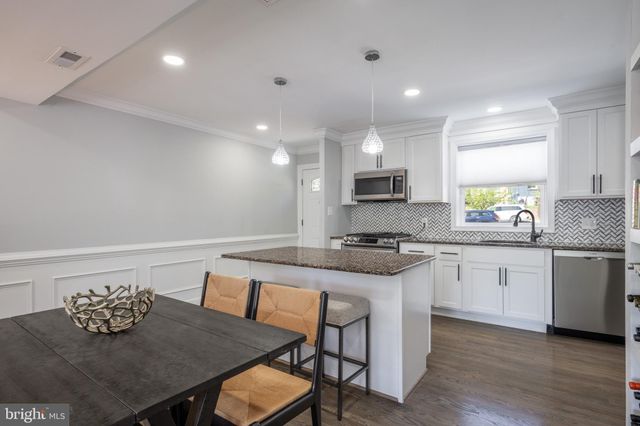 a kitchen with granite countertop stainless steel appliances a sink a stove a table and chairs