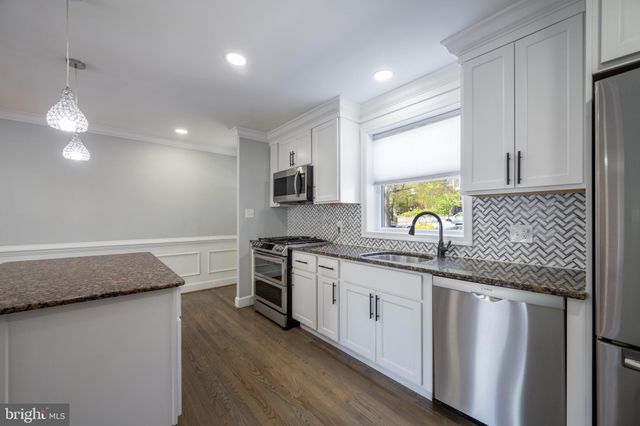 a kitchen with granite countertop a sink a counter space appliances and cabinets