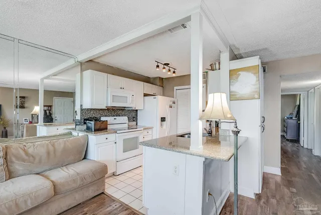 a living room with stainless steel appliances furniture a rug and a view of kitchen