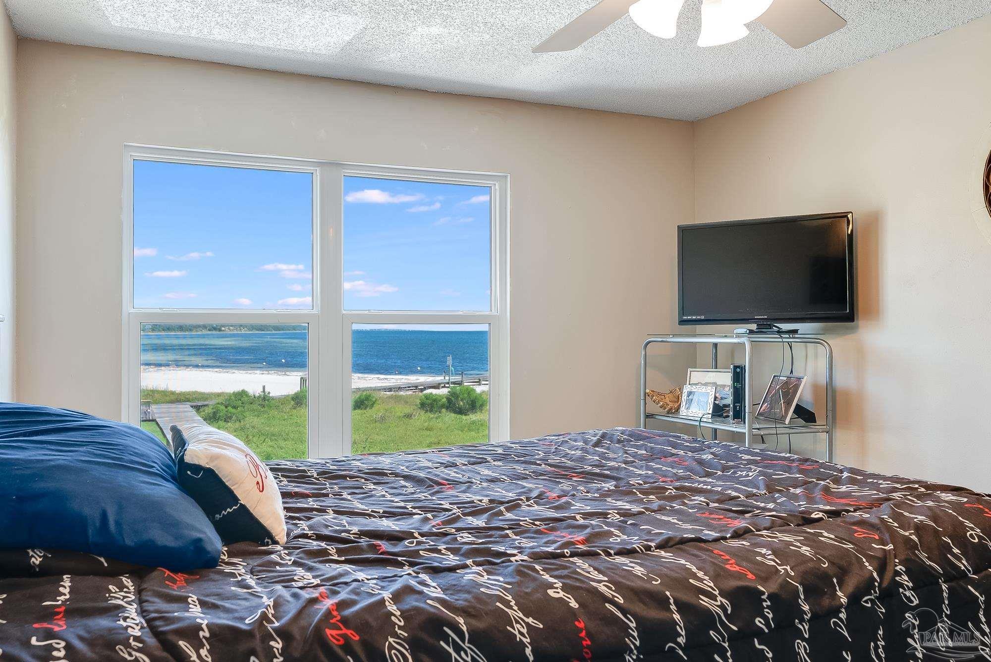 200 Pensacola Beach Road, Unit D2 Gulf Breeze, FL 32561 - Photo 2 of 40 a bedroom with a bed and a flat tv screen next to a window