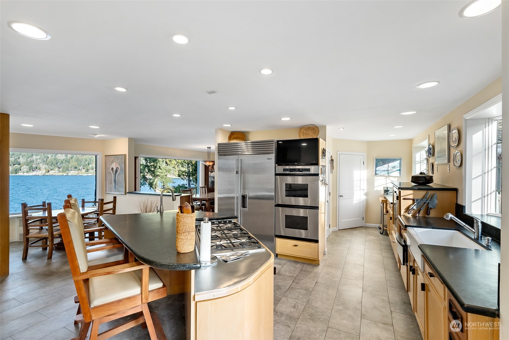 316 Chuckanut Point Road Bellingham, WA 98229 - Photo 19 of 40 a kitchen with stainless steel appliances kitchen island granite countertop a stove a refrigerator a oven a sink a dining table and chairs with wooden floor