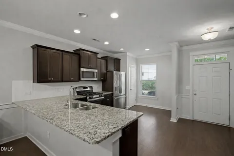 an empty room with wooden floor and kitchen view