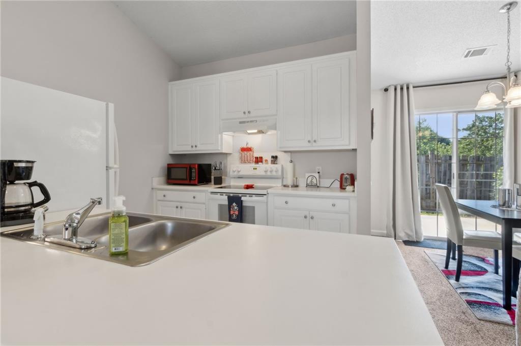 2905 Florence Drive Gainesville, GA 30504 - Photo 14 of 32 a kitchen with stainless steel appliances granite countertop a sink dishwasher and white cabinets next to a window