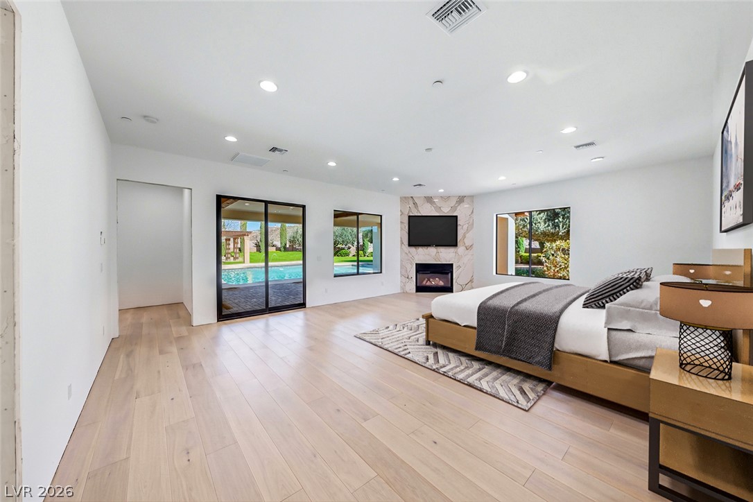 1140 Julie Road Henderson, NV 89002 - Photo 68 of 71 Hardwood floors and a marble fireplace distinguish this spacious primary bedroom with direct pool access.