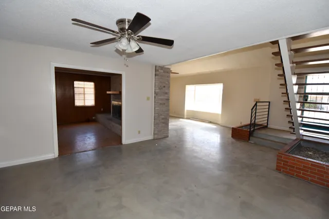 an empty room with windows and fan