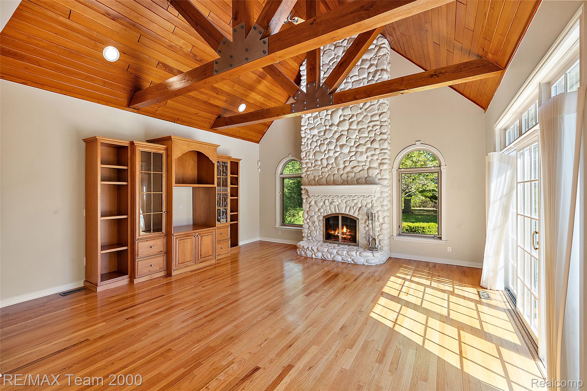 630 Sheldon Court Rochester, MI 48306 - Photo 34 of 94 Unfurnished living room with a fireplace, light wood-style floors, and a high wooden beamed ceiling