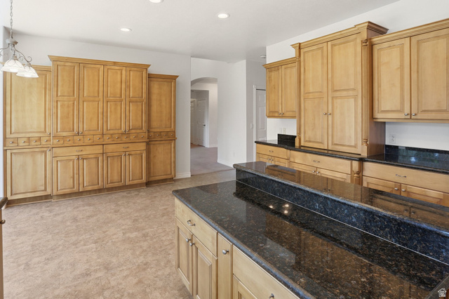 2190 750 West Perry, UT 84302 - Photo 19 of 42 Expansive kitchen featuring abundant wood cabinetry, dark granite countertops, a large center island, built-in pantry storage, and recessed lighting