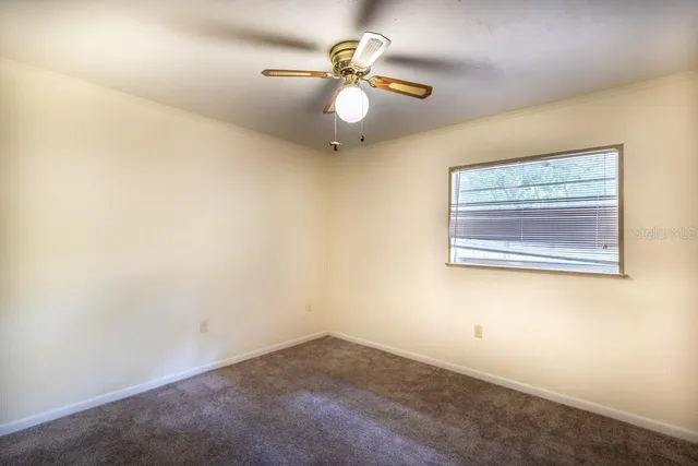 an empty room with a window and a ceiling fan