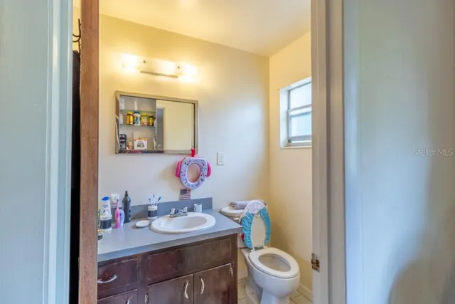 a bathroom with a granite countertop sink a toilet and a mirror