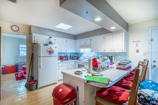 a utility room with stainless steel appliances furniture and a wooden floor
