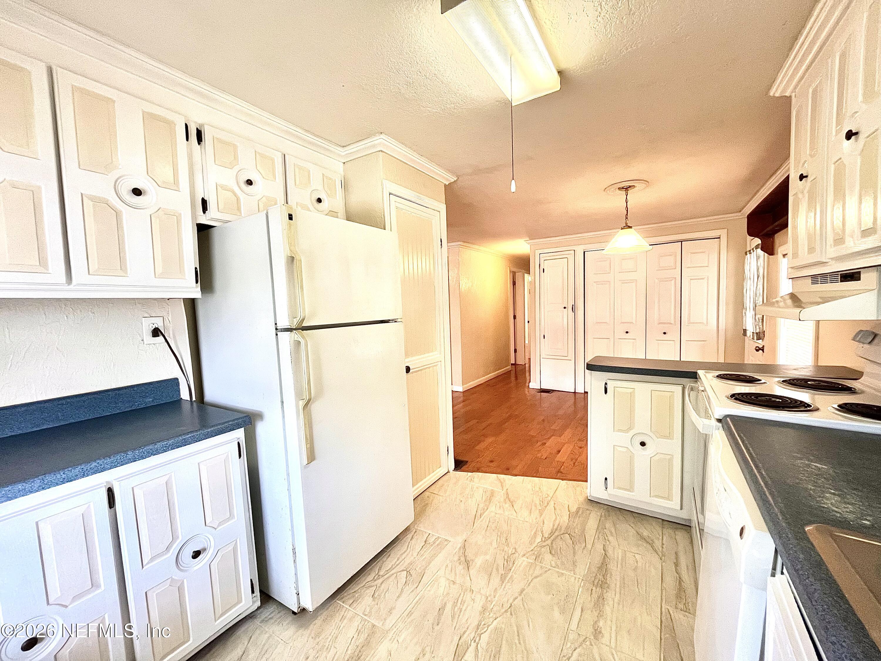 145 Magnolia Trail Satsuma, FL 32189 - Photo 11 of 20 a kitchen with granite countertop a refrigerator a sink and white cabinets