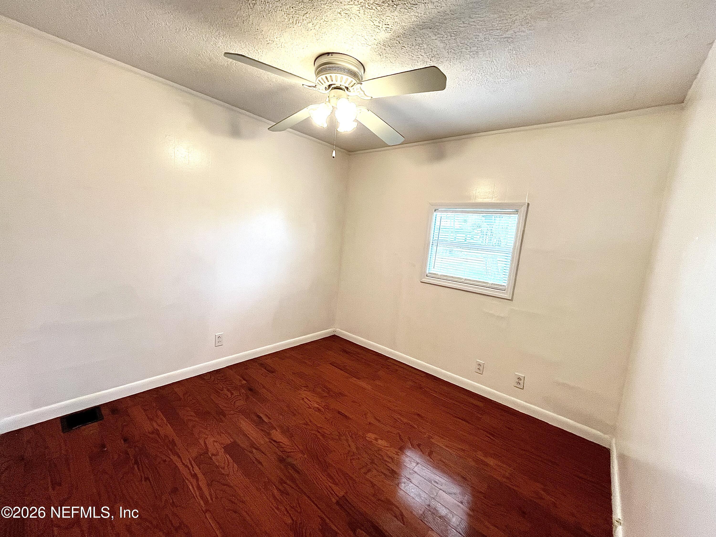 145 Magnolia Trail Satsuma, FL 32189 - Photo 13 of 20 an empty room with a chandelier fan and wooden floor