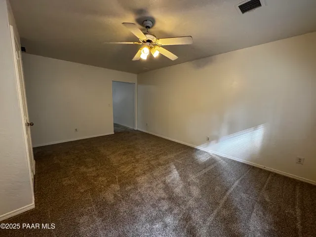 an empty room with a chandelier fan and windows