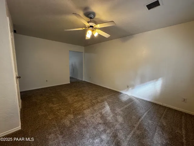 an empty room with a chandelier fan and windows
