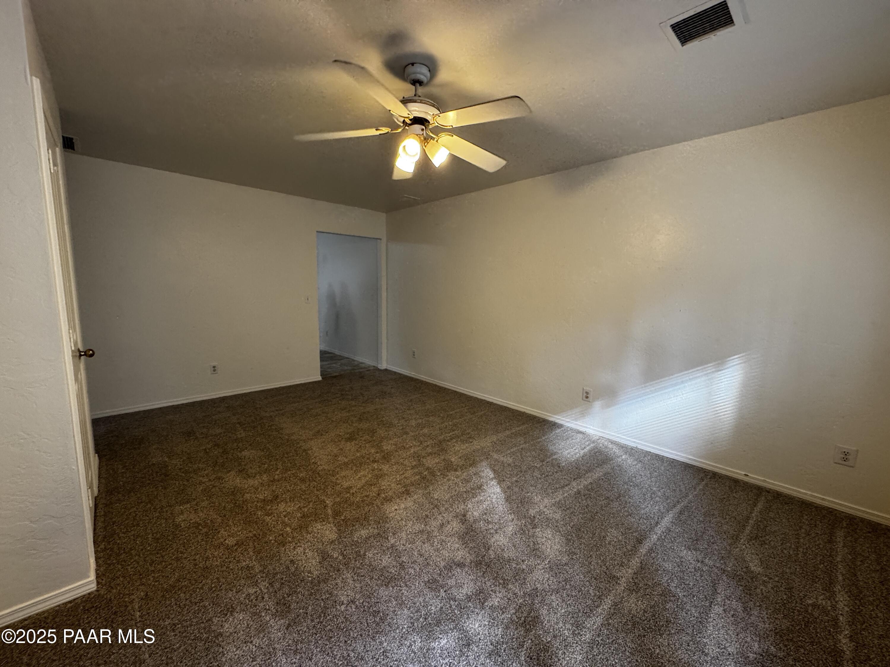 719 Bird Street, Unit B Prescott, AZ 86301 - Photo 9 of 12 an empty room with a chandelier fan and windows
