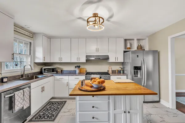 a kitchen with stainless steel appliances granite countertop a sink stove refrigerator and cabinets