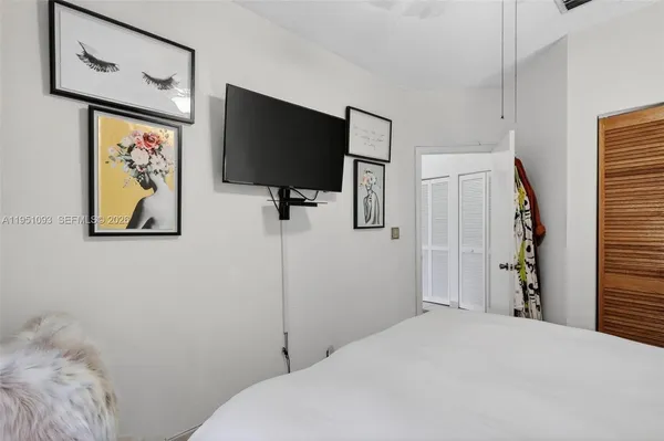 a bedroom with a bed and a flat tv screen on the dresser