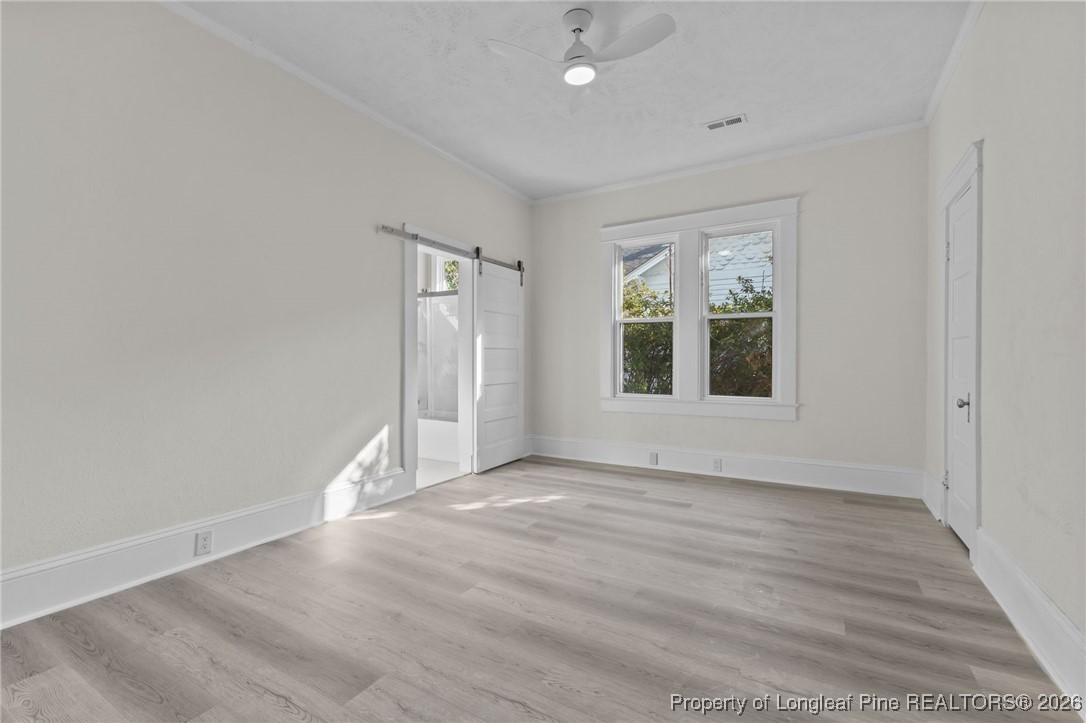 220 Beaman Street Clinton, NC 28328 - Photo 20 of 32 an empty room with wooden floor and windows