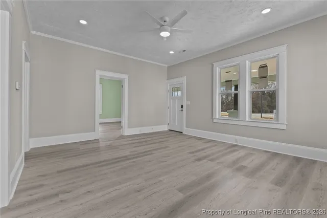 a view of an empty room with wooden floor and a window