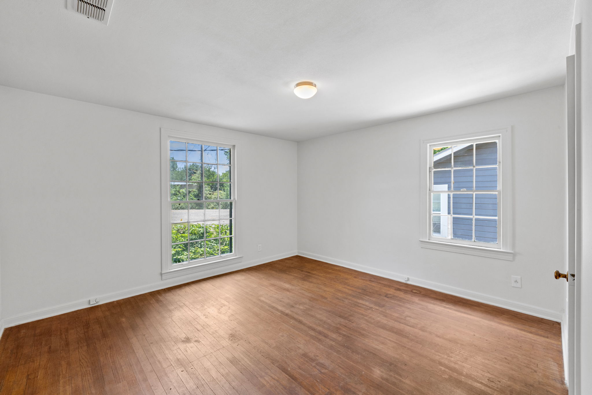 3704 Cherrywood Road Austin, TX 78722 - Photo 25 of 40 Well-lit room features classic hardwood floors and multiple windows inviting natural light.