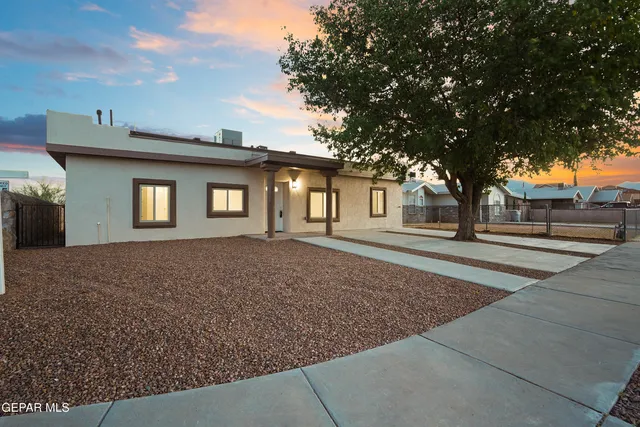 a view of a house with large tree and wooden fence