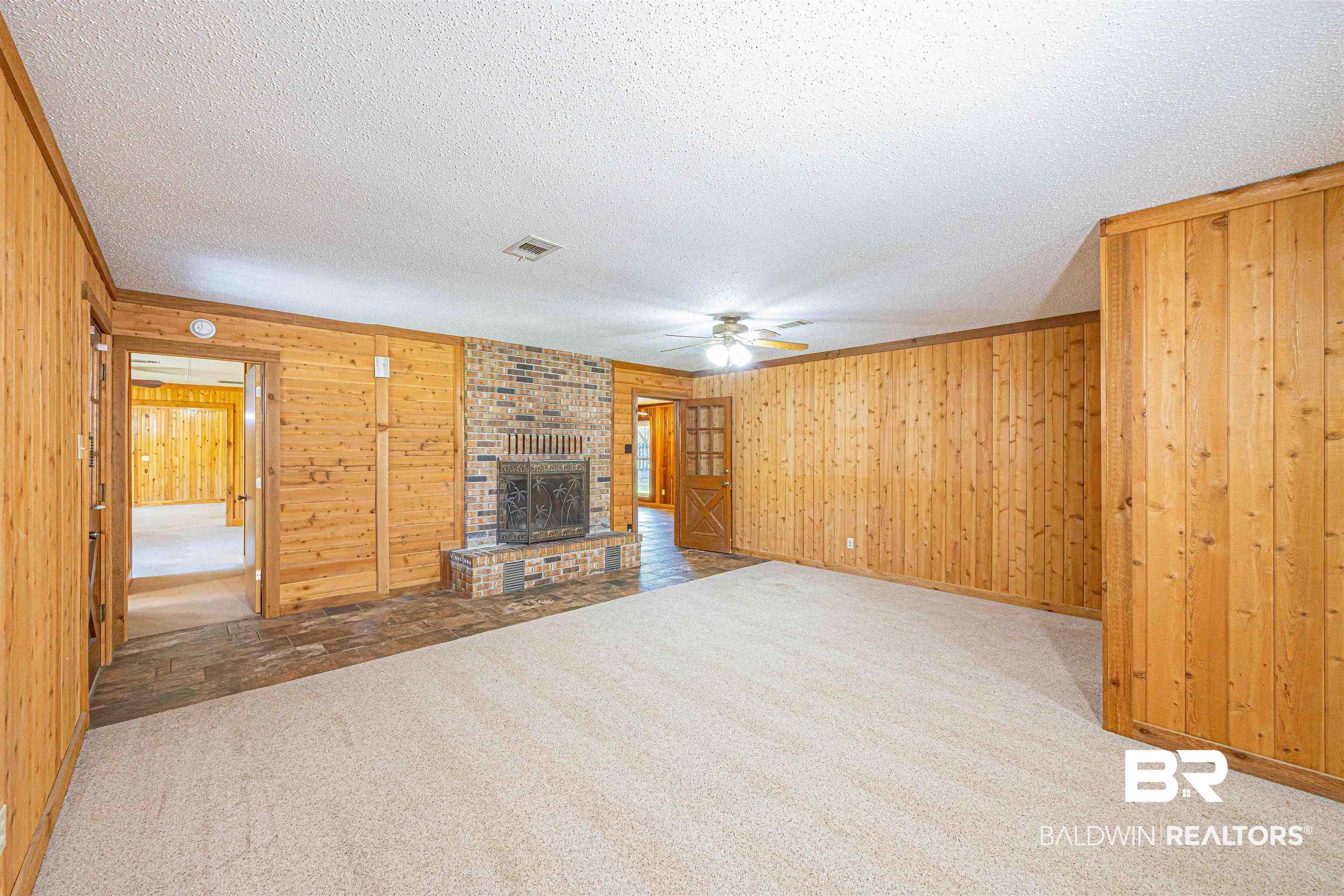 43101 Brown Road Bay Minette, AL 36507 - Photo 21 of 81 Unfurnished living room with carpet floors, wood walls, a fireplace, ceiling fan, and a textured ceiling