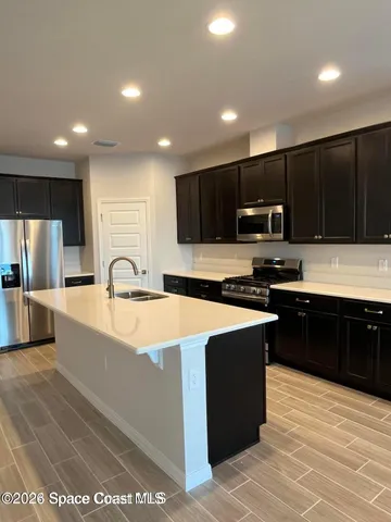 a large kitchen with stainless steel appliances kitchen island granite countertop a stove a sink a refrigerator and a microwave