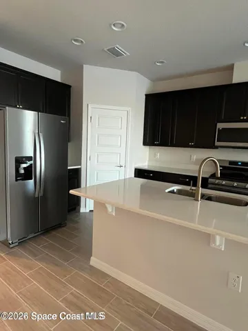 a living room with stainless steel appliances kitchen island granite countertop a refrigerator and a stove top oven