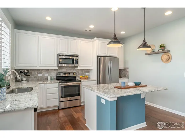 a kitchen with kitchen island a sink stainless steel appliances and white cabinets