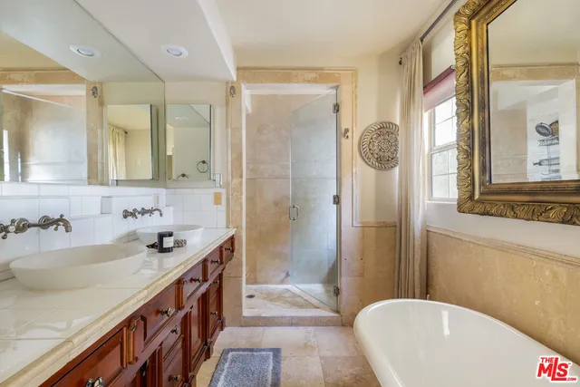 a bathroom with a tub a sink and a large mirror
