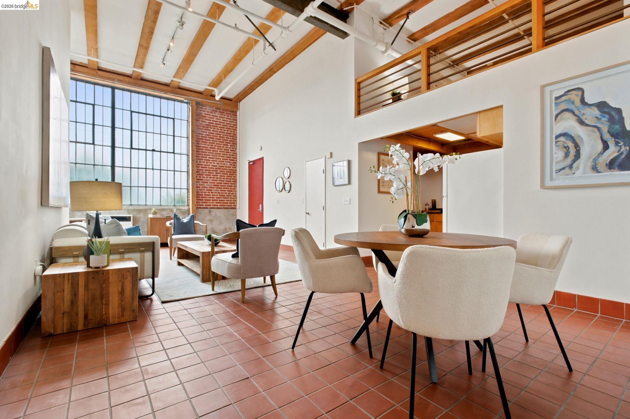1920 Union Street, Unit 9 Oakland, CA 94607 - Photo 10 of 35 Loft-style living area featuring high ceilings with exposed wood beams, large industrial-style windows, and terracotta tile flooring