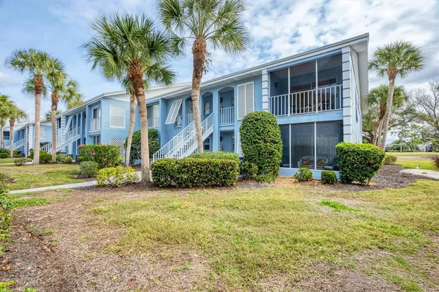 a view of a house with a yard and palm trees