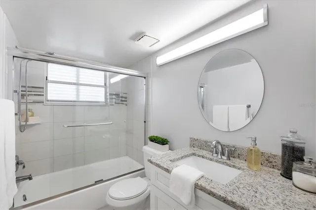 a bathroom with a granite countertop sink a toilet and shower