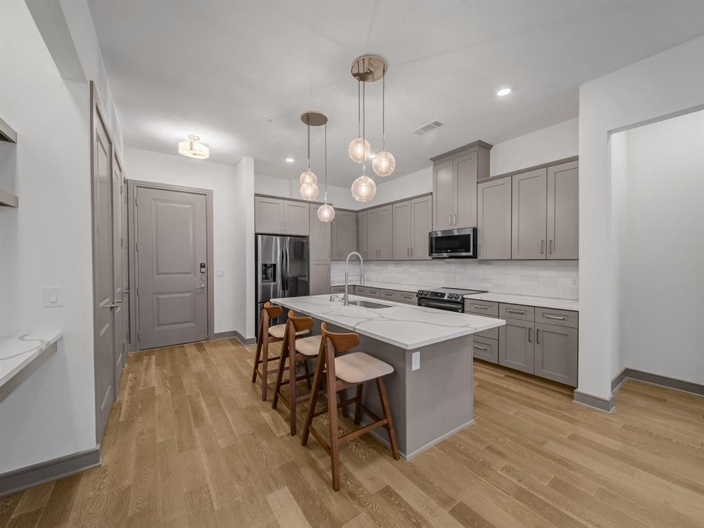 a kitchen with a refrigerator a sink dishwasher a stove and white cabinets with wooden floor