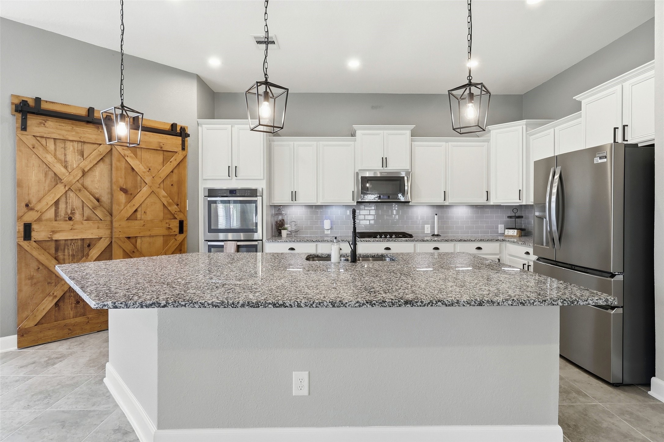 24126 Cane Fields Road Katy, TX 77493 - Photo 1 of 36 Well-appointed modern kitchen overlooking the heart of the home, complemented by an expanded custom walk-in pantry with a sliding barn door for exceptional storage and organization.