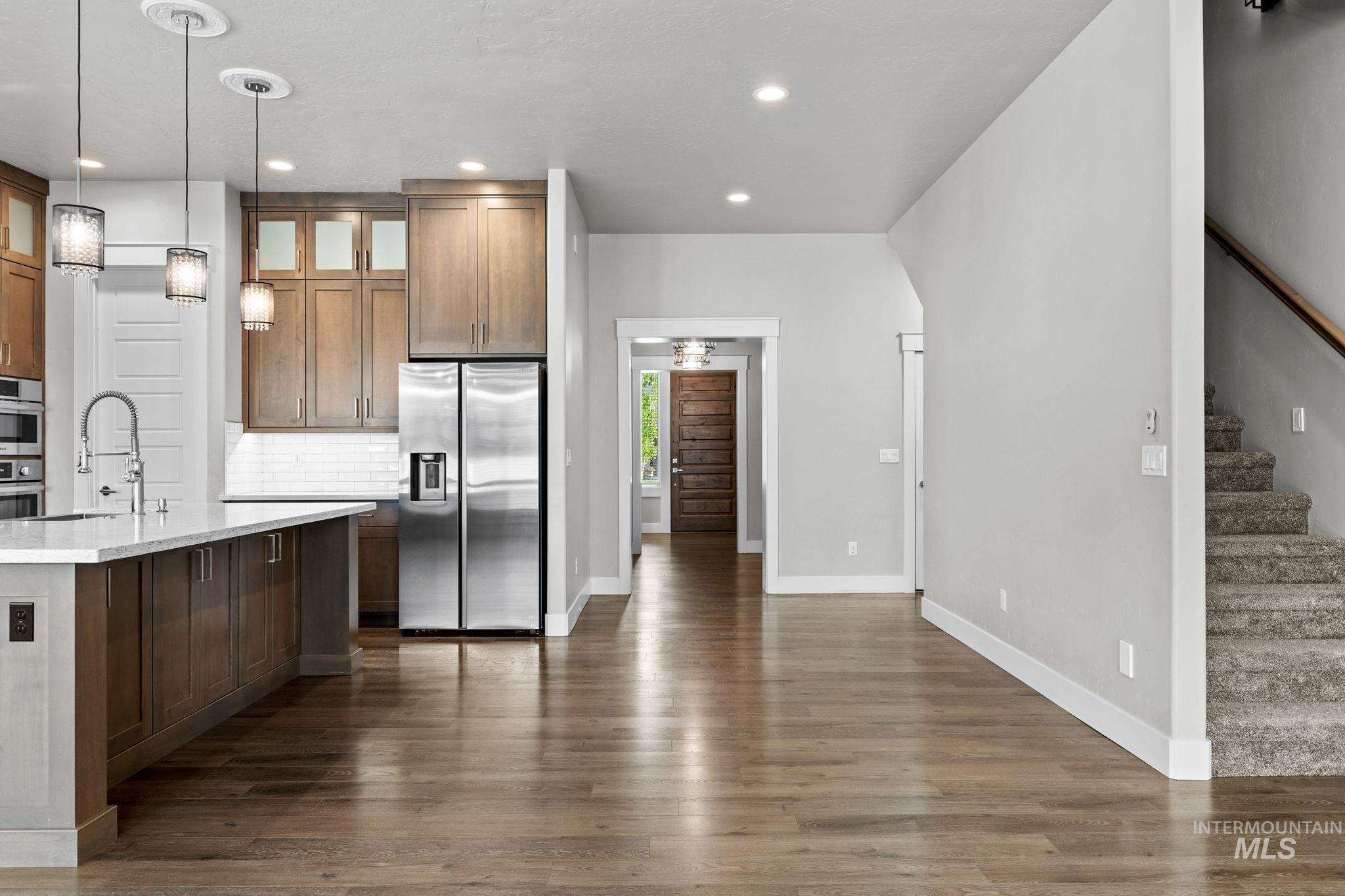 2934 East Murchison Street Meridian, ID 83642 - Photo 7 of 44 Open-concept kitchen featuring wood-finish flooring, a kitchen island with sink, stainless steel appliances, pendant lighting, and recessed lighting