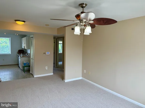 an empty room with a chandelier fan and wooden floor
